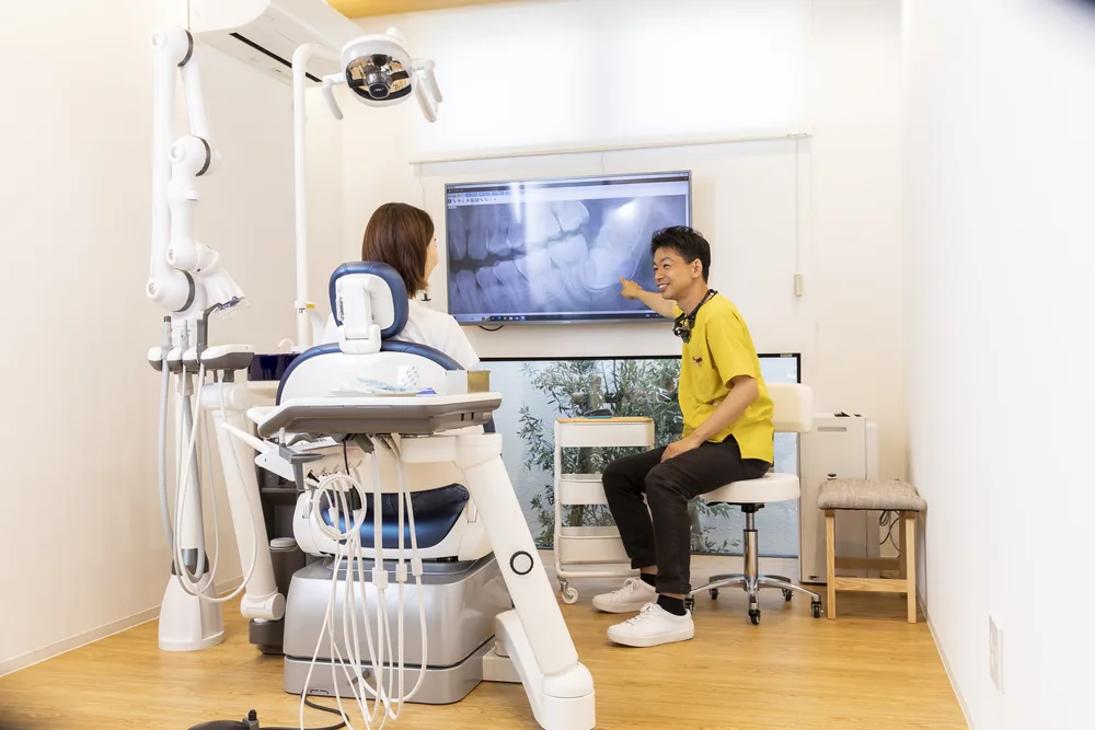 診療室でモニターのレントゲン画像を見ながら治療内容を説明している様子